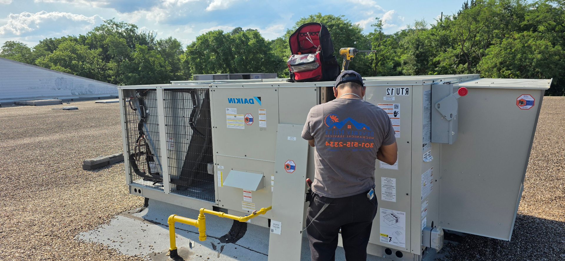 BHMS technician servicing a rooftop Daikin HVAC unit